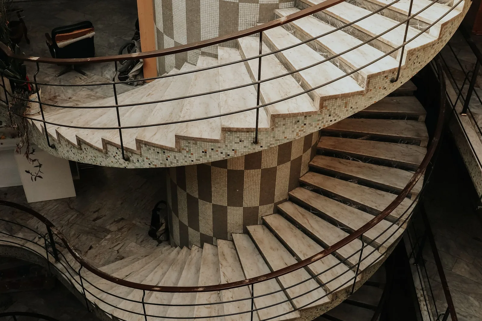 A stone spiral staircase photographed from above, winding down past several floors of a building.