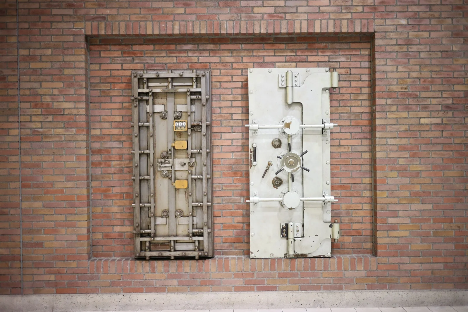 Two steel vault doors set into a red brick wall.