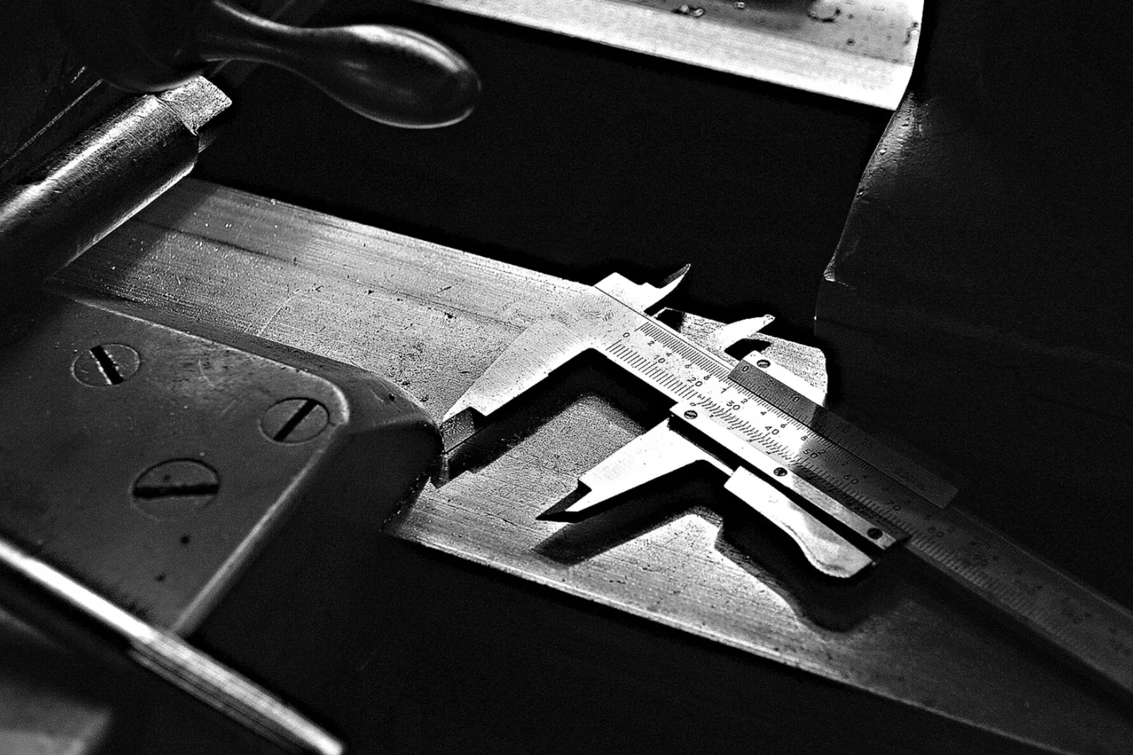 A vernier caliper lying on a machinist's bench, photographed in black and white.