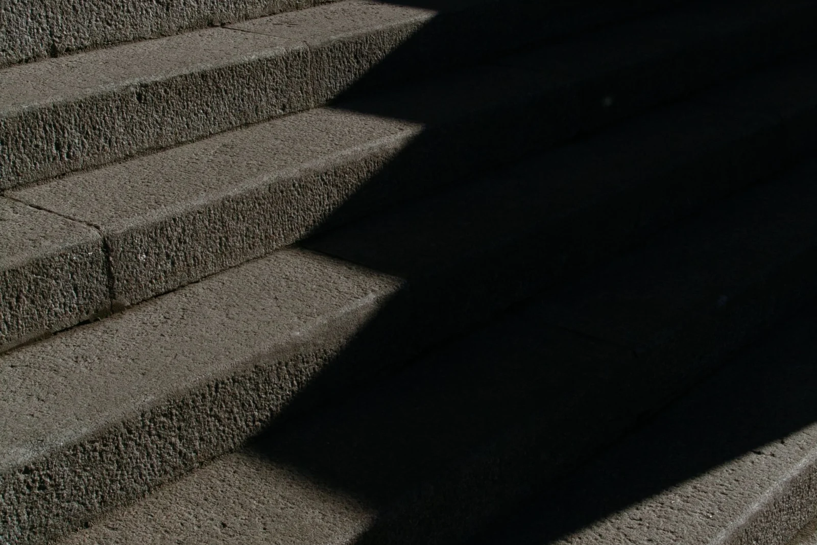 A flight of stone steps in sunlight, with a hard diagonal shadow falling across them.