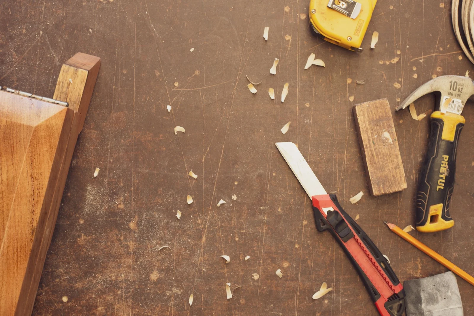 Woodworking tools and a planed timber offcut laid out on a scarred workbench.