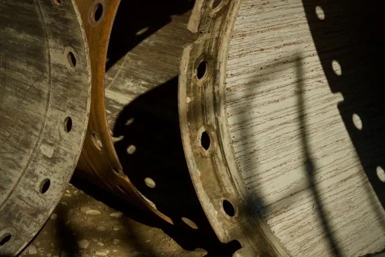 Two steel pipe flanges with bolt holes, lit from the side.