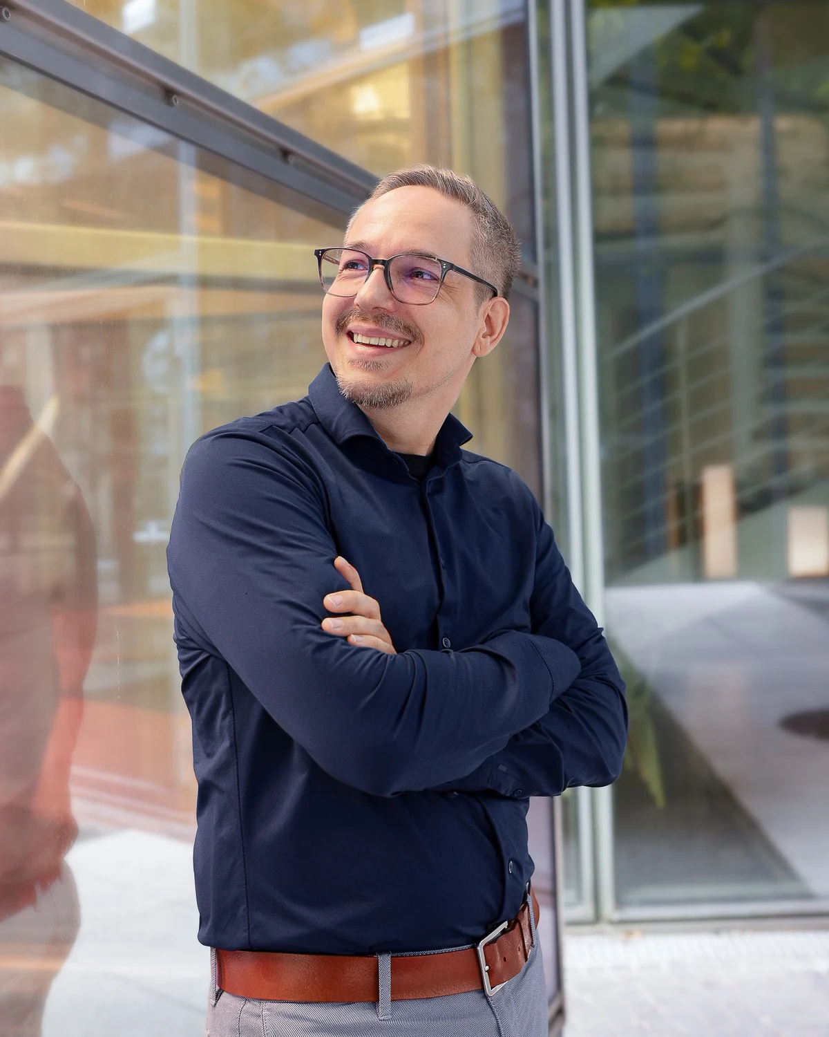 Daniel Förster, smiling, leaning against a glass facade.