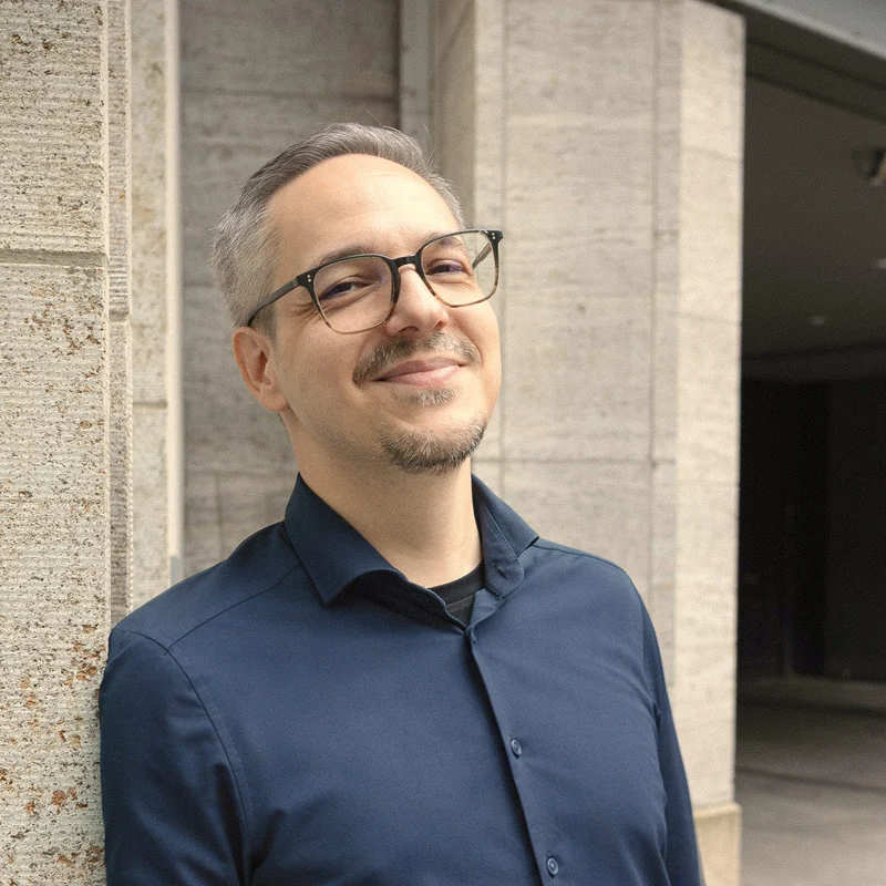 Daniel F&ouml;rster, smiling, leaning against a stone wall.