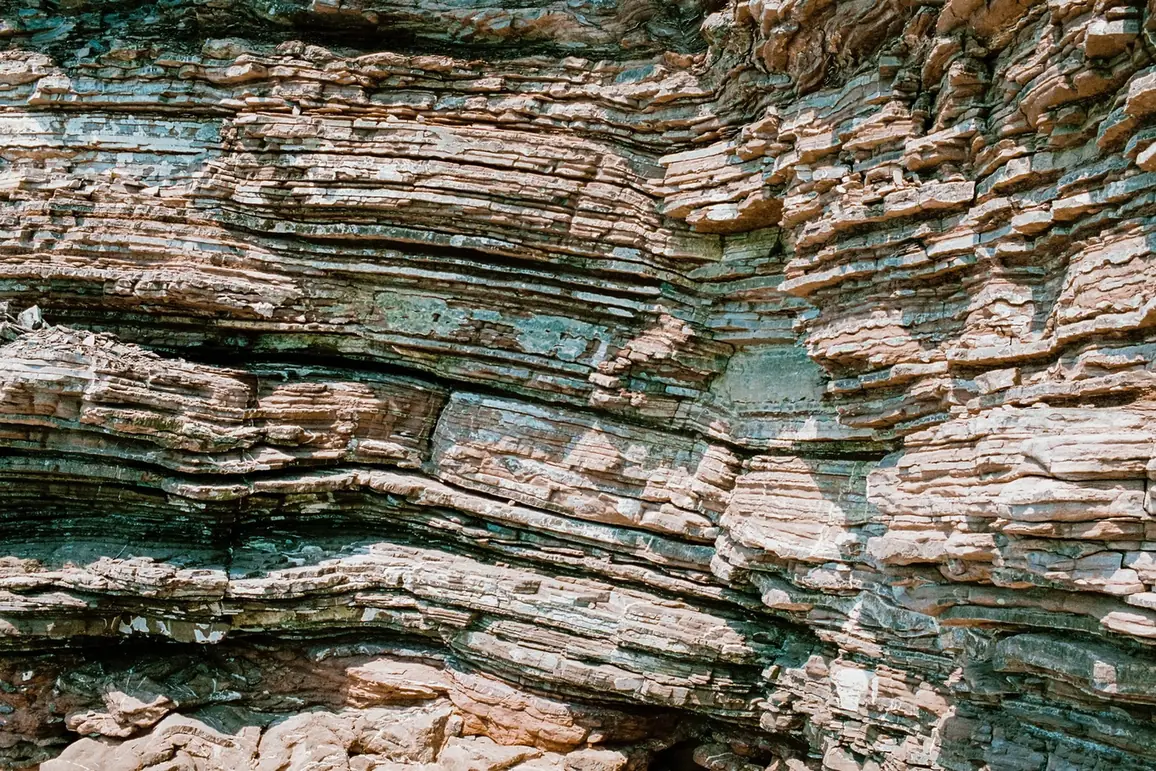 A close view of a rock face showing many thin horizontal layers of stone pressed on top of one another.