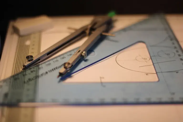 A drafting compass and a set square lie on a sketchpad over a half-drawn geometric construction.