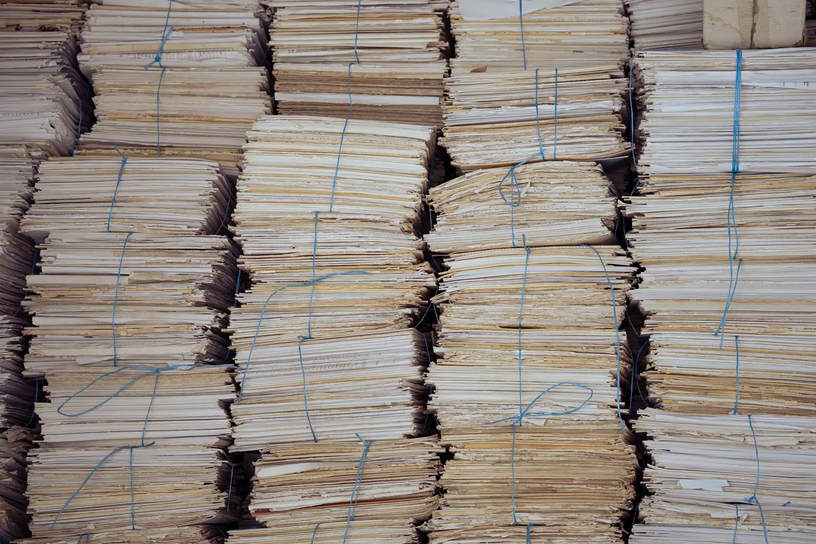 Tall stacks of paper files, each bundle tied with string, filling the frame from side to side.