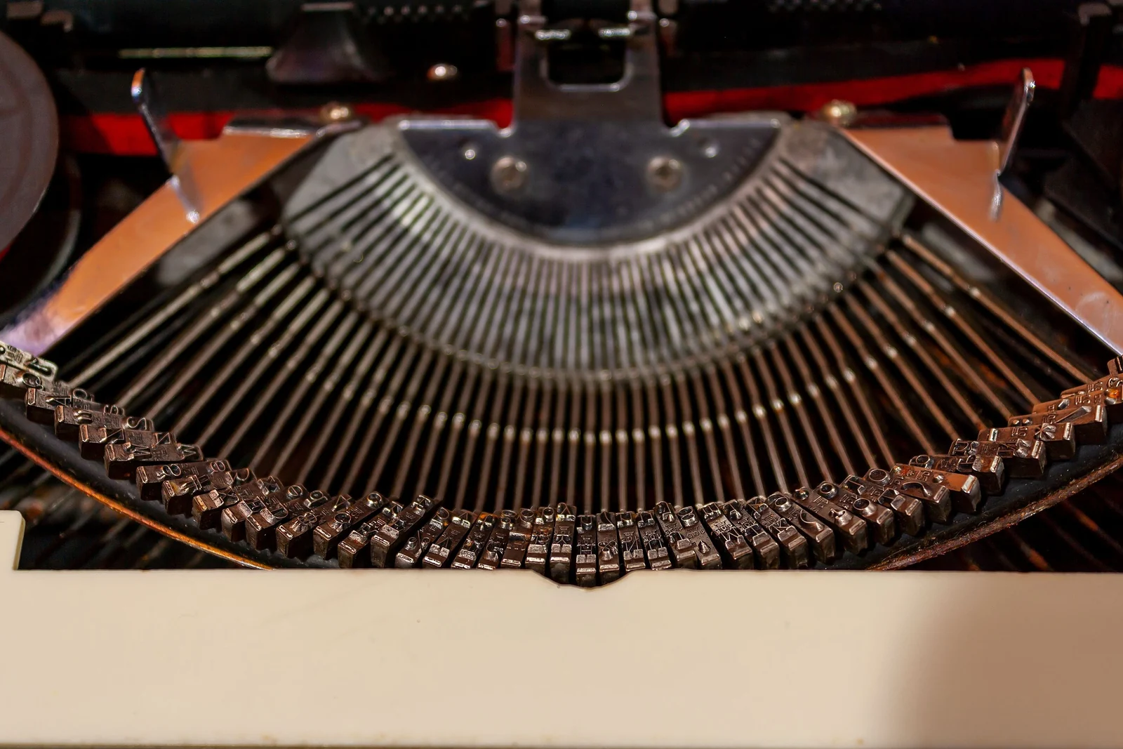 The fan of metal typebars inside an old typewriter, each bar lined up beside the next.