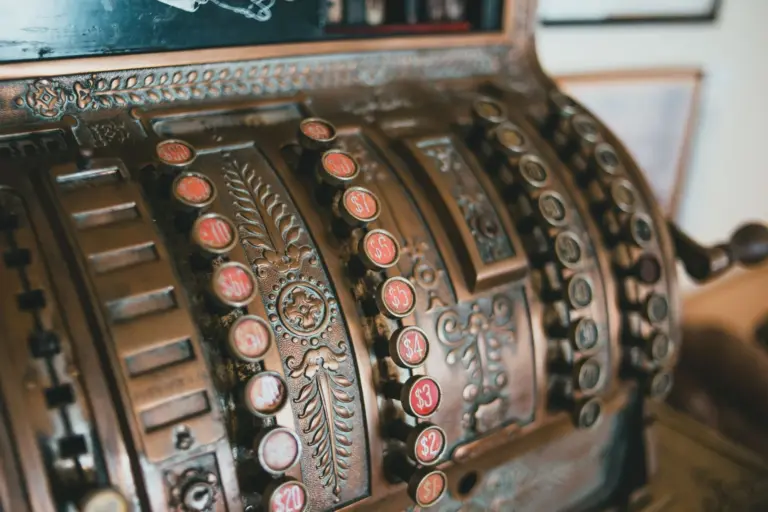 The ornate brass keys and number tabs of an antique cash register, seen close up from the side.