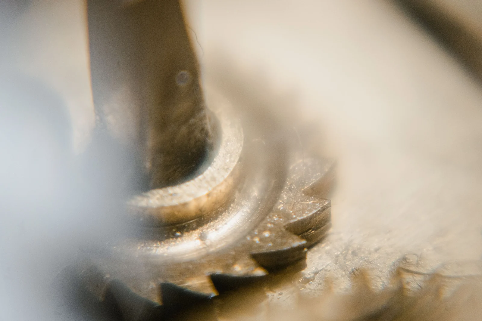 A macro shot of two metal gears meshing, with most of the frame in soft focus.