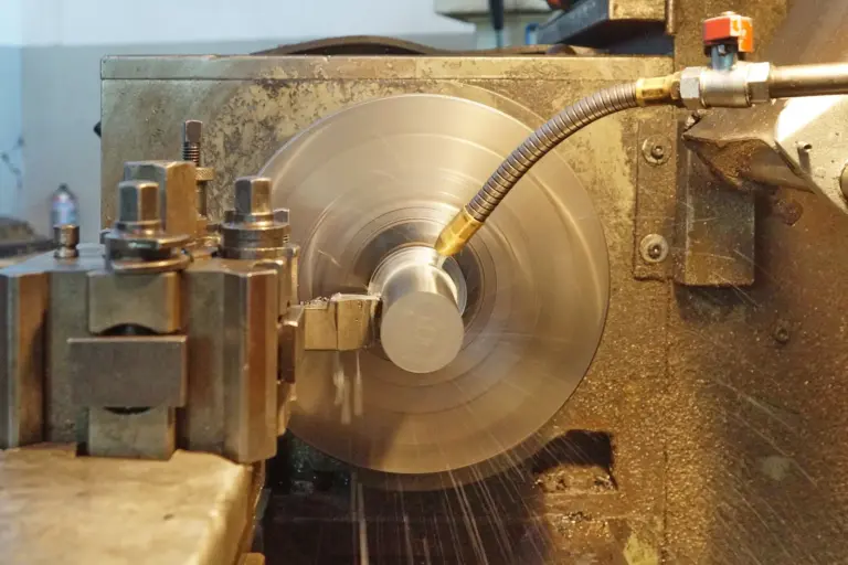 A metal lathe at work, its spinning chuck blurred and a coolant pipe bent over the workpiece.